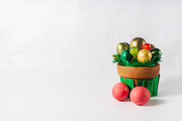 Easter holiday concept. Pot with colored eggs and sweets on a white background