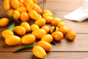 Fresh ripe kumquats with green leaves on wooden table