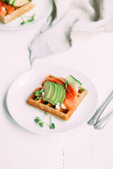 Belgian waffles with salmon, avocado and cream cheese on a white plate. Healthy breakfast