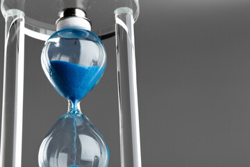 Blue hourglass on gray background close up