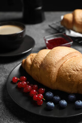 Plate with fresh crispy croissant and berries on grey table, closeup