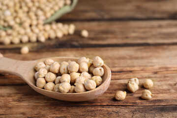 Spoon with chickpeas on wooden table, closeup. Space for text