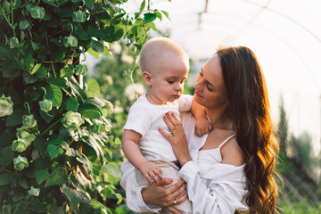 Woman playing with her child in a greenhouse with flowers