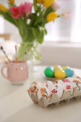 Beautifully painted Easter eggs on white table indoors, space for text