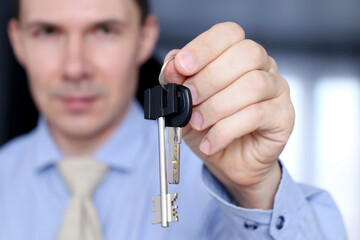 Real estate agent, apartment keys in male hands. Happy man in office clothes, concept of purchase or rental home