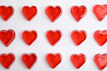 Sweet heart shaped jelly candies on white background, flat lay