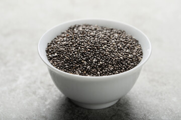 Bowl with chia seeds on grey table