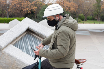 A man in a medical mask chooses to ride a bicycle to get at the office to avoid crowding in public transport during a pandemic, an epidemic