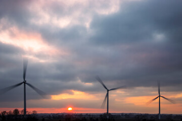 Three wind turbines with dramatic sunset sky