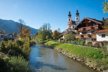 Fototapeta na wymiar pictorial autumn scenery, Aschau im Chiemgau, church with twin tower and prien river, tourist resort upper bavaria