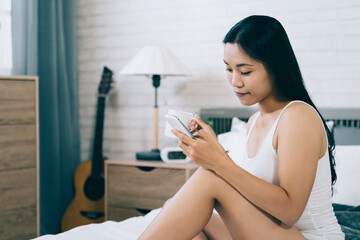 portrait of taiwanese beauty holding coffee and using phone with a smile. pretty Asian young lady...