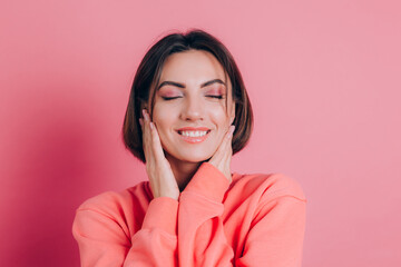 Portrait of beautiful smiling cute brunette woman model in casual peach sweater clothes with bright makeup and pink lips isolated