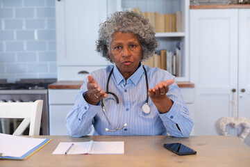Portrait of african american senior female doctor talking looking at the camera at home