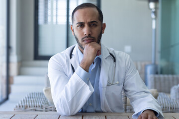 Portrait of caucasian male doctor looking at the camera and rubbing his chin