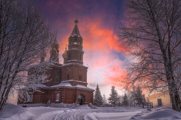 Church at sunset. Trees the branches are covered with thick white frost. The oak shines from the sun, the rays of dawn illuminate  tree and the dome of the cathedral