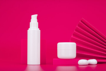 Face cream or lotion in white tube and under eye gel or lip balm in jar against pink background decorated with waver. Concept of set for skin care and beauty in asian style or luxury skin care product
