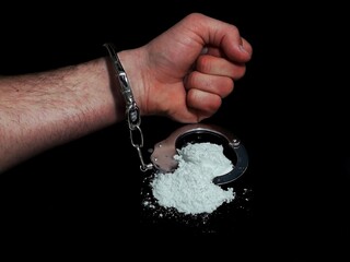 Handcuffed man and cocaine drug powder pile, arrested drug dealer