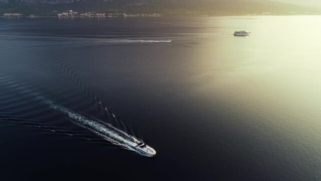 Aerial cinematic view of luxury speed boat sailing in Mediterranean sea in Europe. Sailing experience on a yacht in France, Monaco, Italy or Croatia. Sun reflection on a calm surface of the sea.