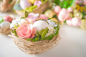 Fototapeta na wymiar Easter greeting card background. Spring tree decor branches with colorful eggs, flowers and leaves on white background copy space for your text