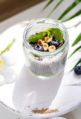 Chia pudding with blueberries, hazelnut, plumeria flower on white wooden stand