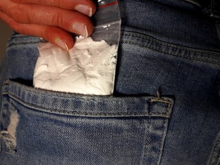 Man puts cocaine drug powder bag into back jeans pocket