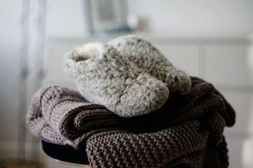 Fototapeta na wymiar Scandinavian living. Warm essentials for the cold season. A knitted blanket and warm woolen shoes.