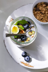 Chia pudding with granola, blueberries, hazelnut on white wooden stand. Top view