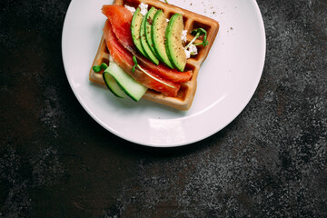 Belgian waffles with salmon, avocado and cream cheese on a white plate. Healthy breakfast