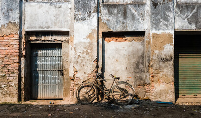 Fototapeta na wymiar A bicycle resting against a grungy wall of the rustic ruins of an old structure in the town of Murshidabad.
