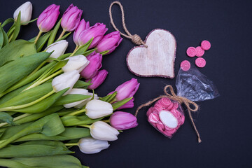 bouquet of pink and white tulips on the left side, wooden heart and lollipops