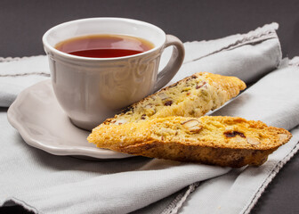 A cup of tea with biscotti cookies on a neutral background