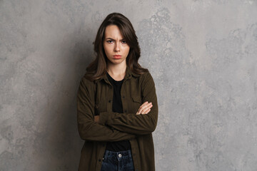 Displeased beautiful brunette girl posing with arms crossed i