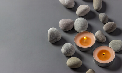 Fototapeta na wymiar Aromatic candles and stones on a gray background. Spa composition. Relaxation and zen like concept. Flat lay. Copy space