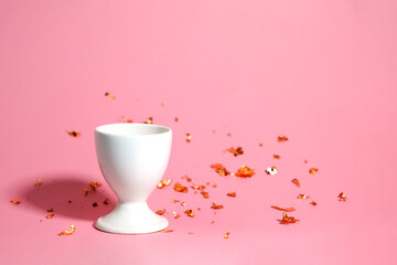 White egg stand on a pink background with blurred gold decor. The background is blurred. Place for your design or lettering.