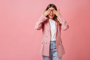 Funny girl in casual jacket covering eyes. Studio shot of trendy lady isolated on pink background.