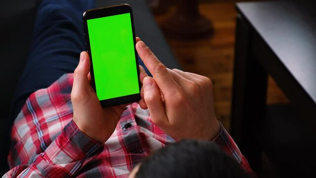 man with a phone in his hands, green screen. Selective focus.