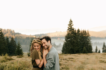 Young happy couple in love hugging and holding hands beautifully in the mountains