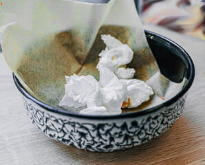 Empty dirty plate with black white pattern after meal with mint napkin inside on wooden table by window in cafe