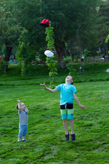 happy kids frolic and jump on the green lawn, throwing up their caps