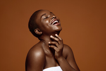 Joyful black woman with short hair touching her flawless skin on neck - Powered by Adobe