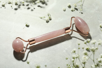 Natural face roller and flowers on grey marble background