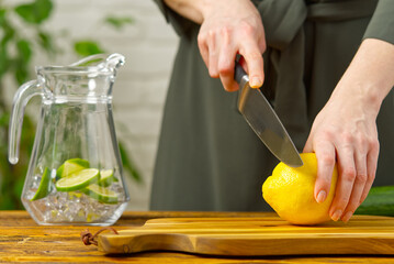 Woman cutting lemon in kitchen, lemon water, Refreshing Water with lime and lemon, healthy eating concept