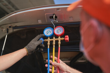 Mechanic male try to check about car air system with manifold gauge