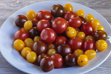 Multicolored tomatoes of different varieties in a dish. Fashionable vegan food.