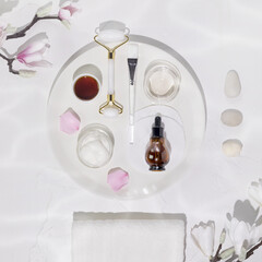 Flat lay, white, cosmetic composition with natural ingredients, beauty accessories, massage stones and magnolia flowers. Skin care lifestyle concept. Preparation for the facials skin care procedure.