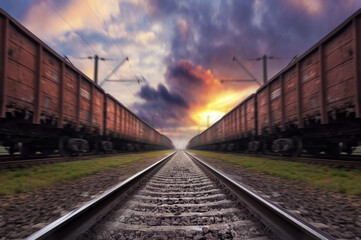 Fototapeta na wymiar Railroad in motion with blur effect at sunset with dramatic sky.