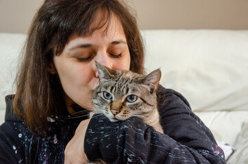 portrait of latin woman holding a tabby cat, cuddling