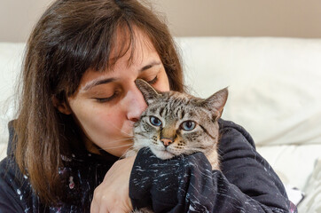 portrait of latin woman holding a tabby cat, cuddling