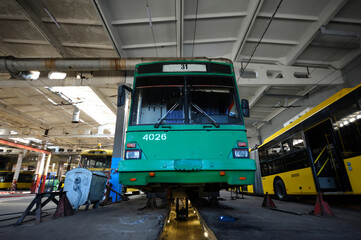 An old but still in use trolleybuses parked on the inspection pit at the trolley depot. Hangar of depot maintenance