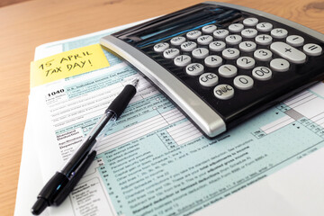 Tax day. 1040 form and calculator on table ready to be filled and returned.